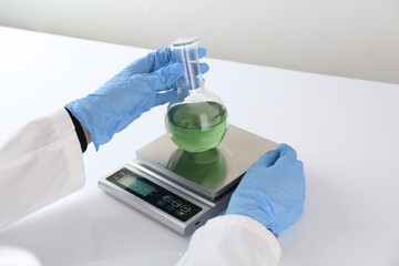Scientist weighing sample on scales at white table, closeup