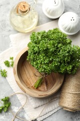 Fresh parsley, oil, spices and thread on grey textured table, flat lay