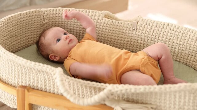 Active newborn baby in bassinet at home