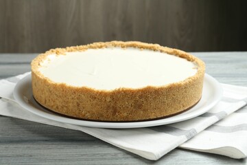 One tasty cheesecake on grey wooden table against brown background, closeup