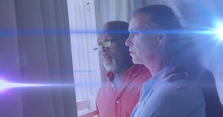 Man placing arm around woman offering support, gazing balcony door, lens flares sweeping in health - Powered by Adobe