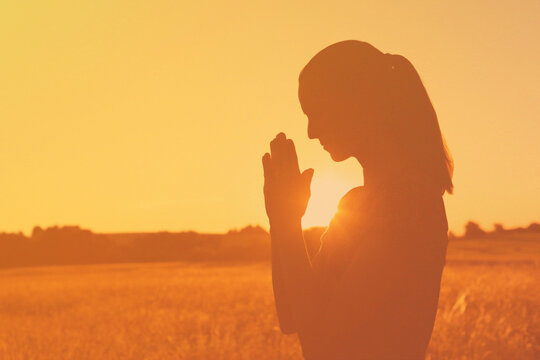 silhouette of girl saying a prayer worshiping god