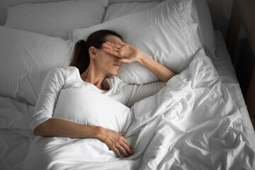 Sleepless woman opening eyes waking up in the bed can't sleep ant night time from symptom of depression stress 