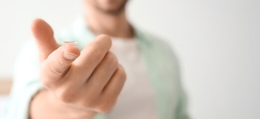 Naklejka premium Young man with contact lens in bedroom, closeup