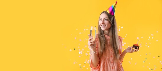 Happy young woman with Birthday cake and glass of champagne on yellow background with space for text