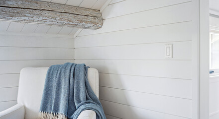 Hamptons coastal chair with blue throw blanket and white shiplap walls, cozy beachhouse seating for luxury home website banners and interior design headers