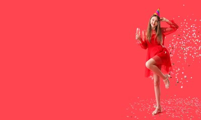Happy young woman with glass of champagne celebrating Birthday on red background with space for text