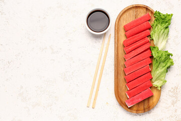 Wooden board with tasty crab sticks and sauce on light background © Pixel-Shot