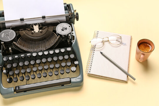 Vintage typewriter with blank paper sheet, glasses, notebook, pencil and cup of coffee on yellow background