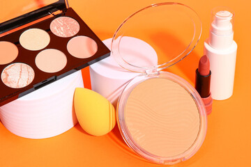 Different makeup cosmetics on orange background, closeup