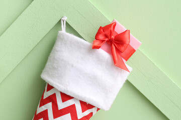 Christmas sock hanging with gift box on green background