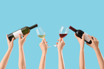 Female hands holding glasses and bottles of different wine on blue background
