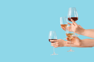 Female hands holding glasses of different wine on blue background