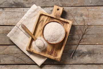 Bowl and spoon with psyllium husk powder on wooden background