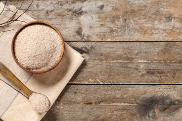 Bowl and spoon with psyllium husk powder on wooden background with space for text