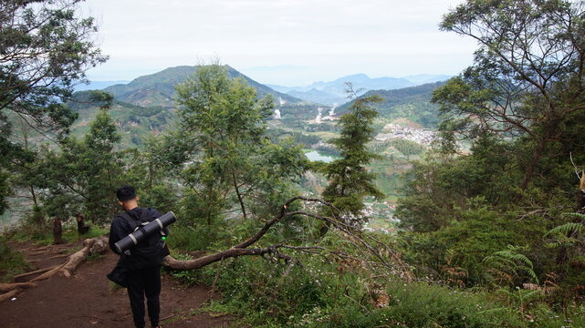A man wearing a black jacket and carrying a mountain climber's backpack is walking down the mountain
