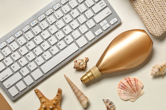 Computer keyboard with sunscreen and beach decor on white background