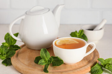 Teapot and cup of hot mint tea on white table