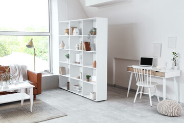 Interior of light living room with shelf unit, sofa and workplace