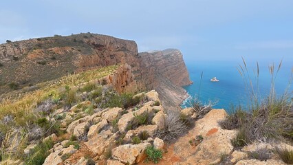 The breathtaking view showcases rocky cliffs dramatically meeting the serene blue ocean waters beneath a foggy sky