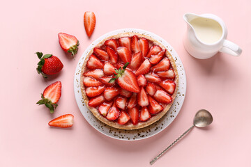Plate with sweet strawberry tart and jug of fresh milk on pink background