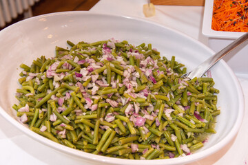 a dish of green beans with chopped red onion, likely a salad or a side dish. Green beans, also...