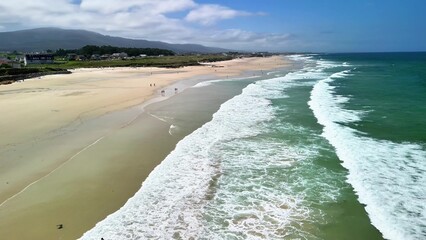 Stunning aerial view showcasing a tranquil beach where gentle waves meet the shore under clear blue...