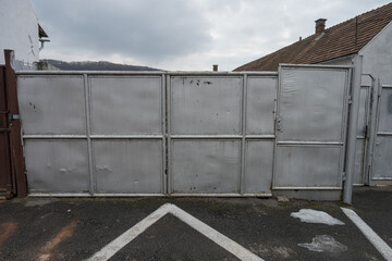  a large, grey metal gate, likely serving as an entrance or barrier to a property. The gate appears...