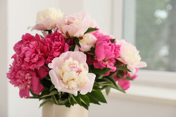 Vase with beautiful peony flowers near window in room, closeup