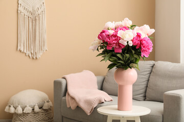 Vase with beautiful peony flowers on table in interior of living room, closeup