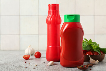 Bottles of tasty ketchup and different ingredients on grey table