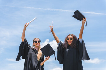 Joyful Graduates Celebrate Success Under Blue Sky, Happy Female Graduates Holding Diplomas and...