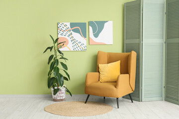 Interior of living room with abstract paintings, armchair and folding screen