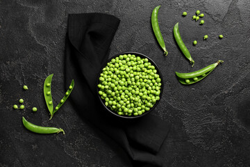 Bowl with fresh green peas on black grunge background