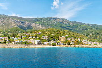 Fototapeta premium Agios Kirykos harbor waterfront cityscape by Icarian sea and church on Ikaria, Greece Greek longevity blue zone island from ferry