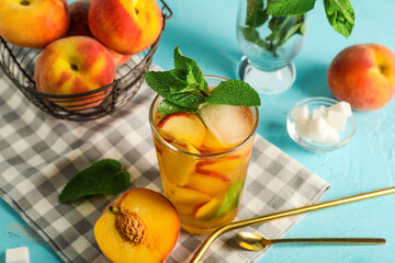 Composition with glass of tasty peach iced tea and napkin on blue grunge background, closeup