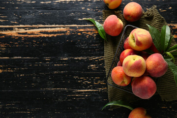 Basket of fresh peaches on dark wooden background, top view