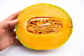 One vibrant colorful yellow cantaloupe muskmelon sol glow melon half cut, hand holding fruit and macro texture of seeds on white background