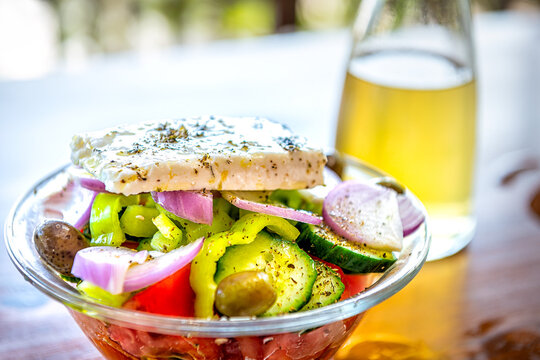Greek salad bowl, traditional homemade meal appetizer on Ikaria Greece, kathoura sheep cheese, vegetables bottle of white wine in background