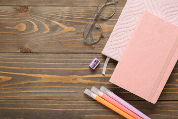 Composition with eyeglasses, notebooks and stationery supplies on wooden background, closeup