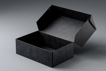 A slightly ajar, matte black rectangular box with a textured surface sits on a gray background.  The interior is dark and empty