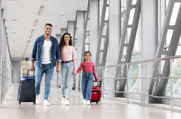 Travel Insurance. Smiling Arabic Family With Daughter Walking With Suitcases At Airport, Happy...