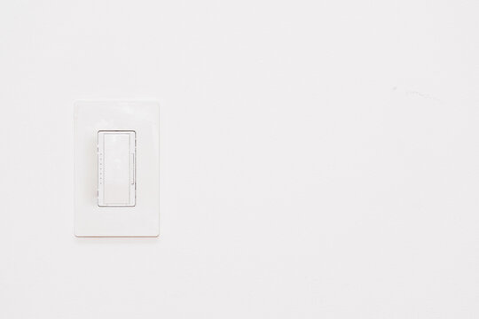 White dimmer light switch on white wall with copy space