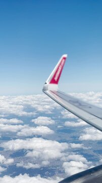 Wing Seen From Passenger Window During Flight Above Clouds - 4K Vertical