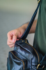 A man with a black leather shoulder bag