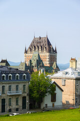 Fototapeta premium Iconic Château Frontenac rises above neighboring slate-roof houses on a bright summer day