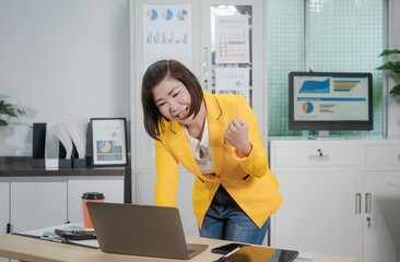 A middle-aged Asian woman sits at a work desk, deeply focused. Surrounded by charts and notes, she...