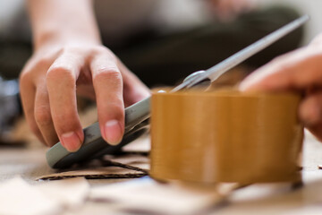 Close Up Of Hands Holding Scissors For Cutting Cardboard