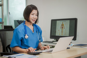 A middle-aged Asian female doctor sits alone at her desk in clinic, attentively reviewing patient...