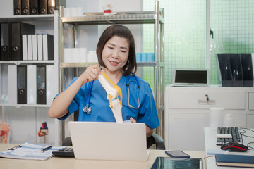 A middle-aged Asian female doctor at her desk,explaining various bone and joint diseases like...
